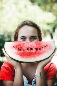 Mädchen hält ein Stück Melone vor ihrem Gesicht